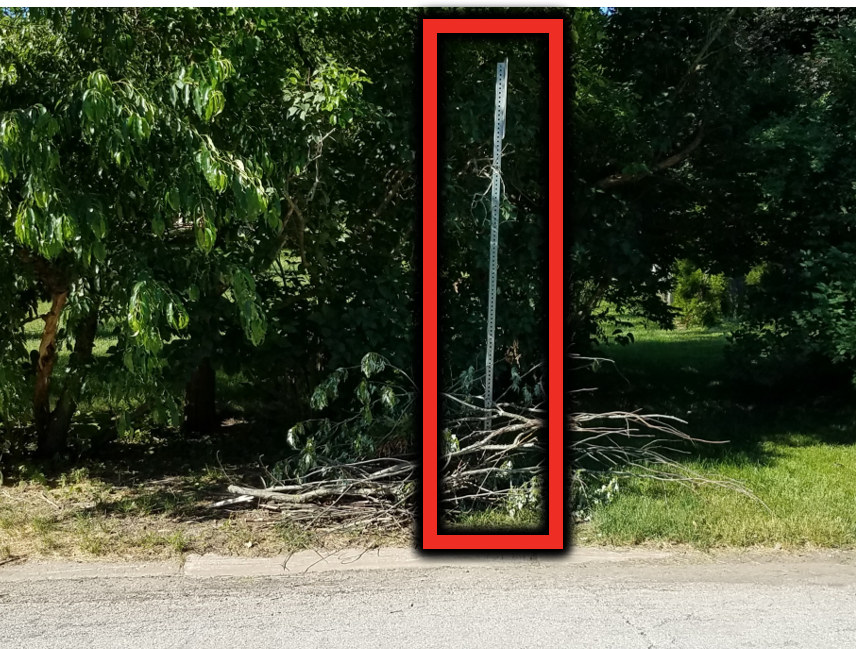 Brush is behind the curb, but it is placed on a road sign