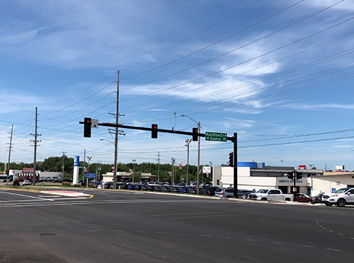 A traffic signal with four red lights at the intersection of GE Road and Keaton Place with new asphalt and traffic lines