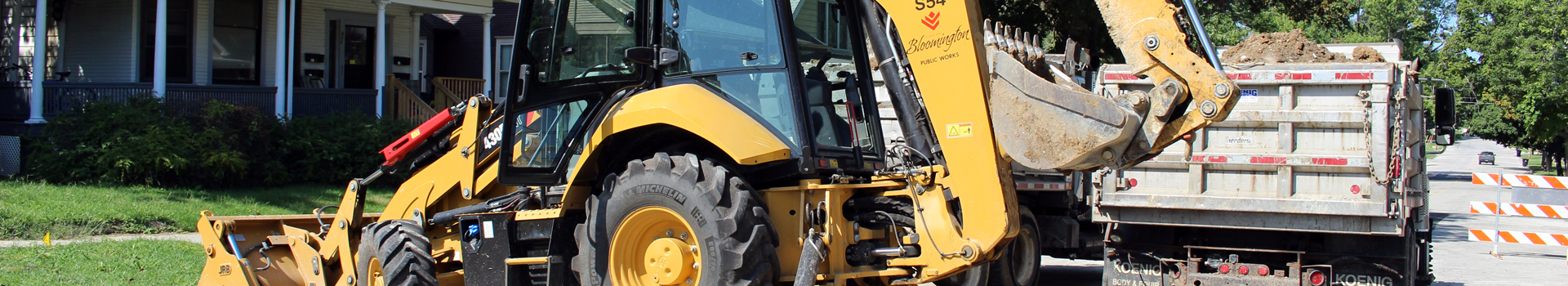 End loader with front and rear buckets with dump truck full of dirt behind it