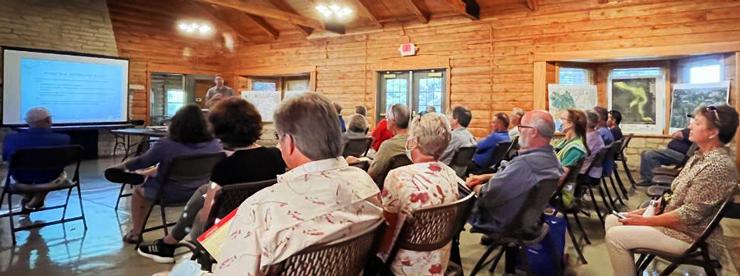 A person giving a presentation to a group of people at a public meeting.