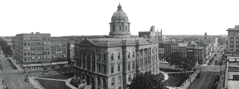 Black and white photo of the old courthouse in Downtown Bloomington with buildings and street around it